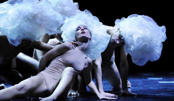 Tre ballerine distese a terra con body color carne e parrucche di plastica 